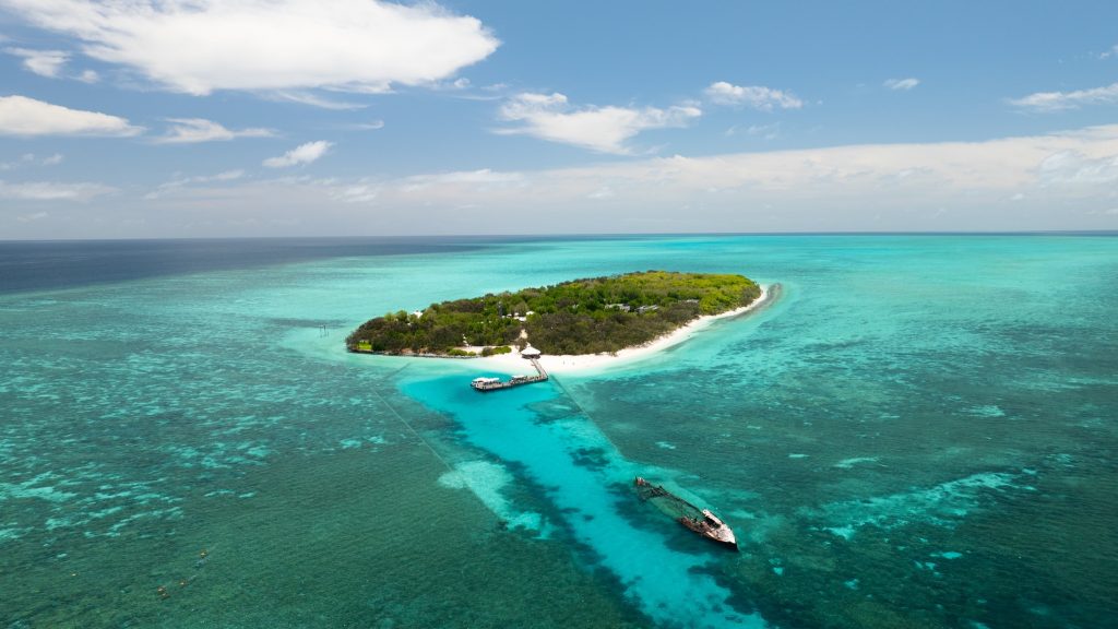 Tropical island surrounded by vibrant turquoise waters and a clear blue sky.